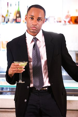 Portrait of a businessman leaning against a bar counter holding a martini glass Stock Photo - Premium Royalty-Free, Code: 625-00838363