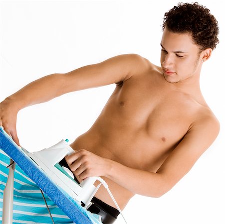 Young man ironing his shirt Stock Photo - Premium Royalty-Free, Code: 625-00838485