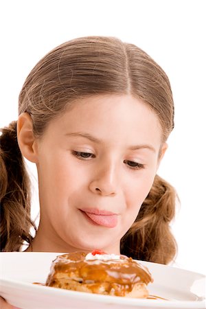 simsearch:625-01251733,k - Gros plan d'une jeune fille tenant un beigne dans une plaque lèche ses lèvres Photographie de stock - Premium Libres de Droits, Code: 625-00838585