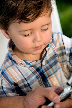Close-up of a boy looking at a mobile phone Stock Photo - Premium Royalty-Free, Code: 625-00849040