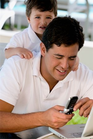 simsearch:625-00849100,k - Nahaufnahme eines Vaters, der mit einem Mobiltelefon mit seinem Sohn hinter ihm stehen Stockbilder - Premium RF Lizenzfrei, Bildnummer: 625-00849628