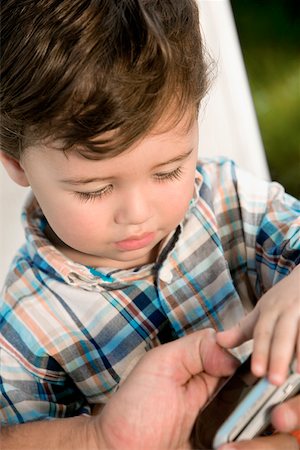 Close-up of a boy looking at a mobile phone Stock Photo - Premium Royalty-Free, Code: 625-00849772