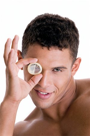 Portrait of a young man looking through a condom Stock Photo - Premium Royalty-Free, Code: 625-00841294