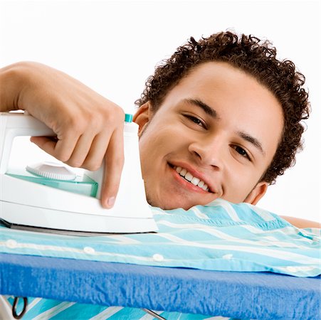 Portrait of a young man ironing his shirt Stock Photo - Premium Royalty-Free, Code: 625-00841339