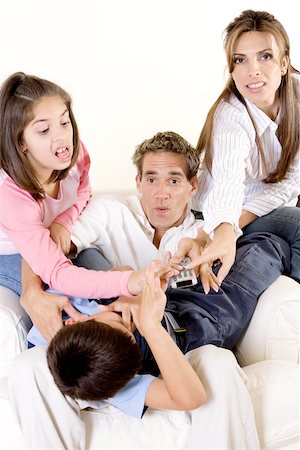 Parents with their son and daughter pressing buttons on a remote control Stock Photo - Premium Royalty-Free, Code: 625-00841364