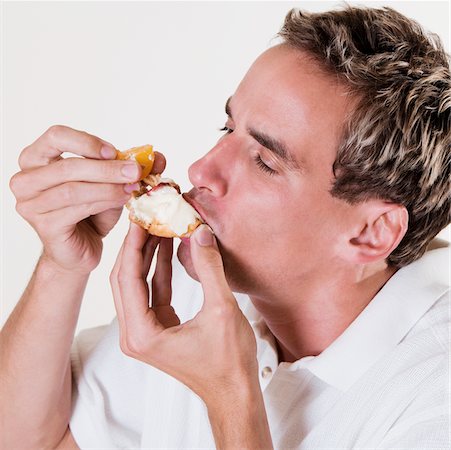 Close-up of a young man eating a strawberry tart Fotografie stock - Premium Royalty-Free, Codice: 625-00841381