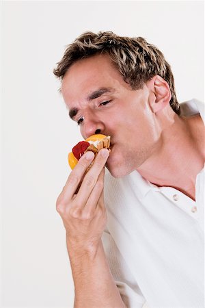 Close-up of a young man eating a strawberry tart Fotografie stock - Premium Royalty-Free, Codice: 625-00841383