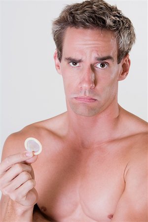 simsearch:625-00851085,k - Portrait of a young man holding a condom Foto de stock - Royalty Free Premium, Número: 625-00841548