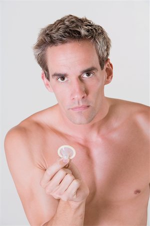 simsearch:625-00851085,k - Portrait of a young man holding a condom Foto de stock - Royalty Free Premium, Número: 625-00841541