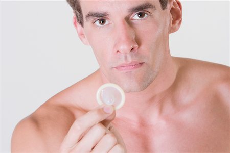 simsearch:625-01252359,k - Portrait of a young man holding a condom Stock Photo - Premium Royalty-Free, Code: 625-00841542