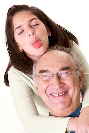 Close-up of a granddaughter sticking out her tongue and hugging her grandfather Stock Photo - Premium Royalty-Free, Code: 625-00841605