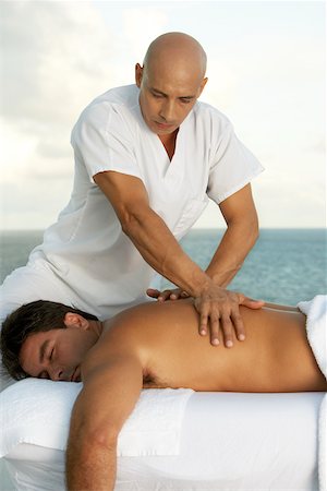 Close-up of a massage therapist giving a young man a back massage Stock Photo - Premium Royalty-Free, Code: 625-00841957