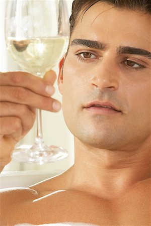 simsearch:625-00900680,k - Gros plan d'un jeune homme tenant un verre de vin blanc dans une baignoire Photographie de stock - Premium Libres de Droits, Code: 625-00841986