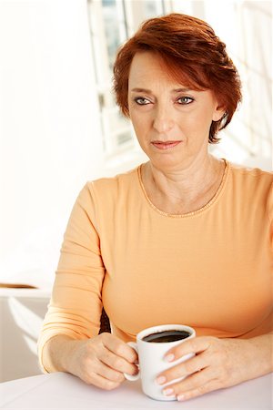 Close-up of a senior woman seated at a table with a cup of coffee Stock Photo - Premium Royalty-Free, Code: 625-00842018