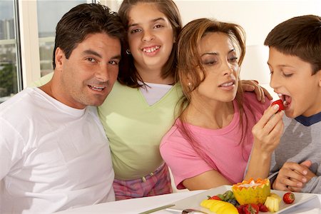 Portrait of a mid adult man with his daughter and mid adult woman feeding her son a strawberry Stock Photo - Premium Royalty-Free, Code: 625-00842035