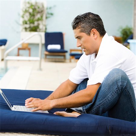 Side profile of a mid adult man using a laptop Stock Photo - Premium Royalty-Free, Code: 625-00843001