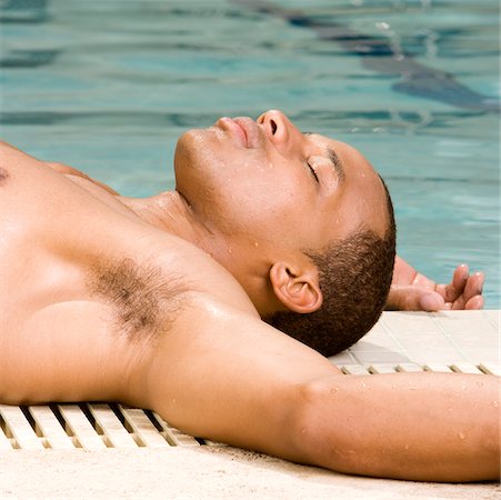 Gros plan d'un jeune homme couché au bord de la piscine Photographie de stock - Premium Libres de Droits, Code: 625-00843483