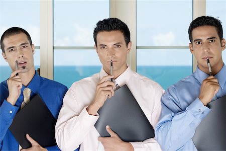 simsearch:625-01096766,k - Portrait of three businessmen holding pens against their faces Stock Photo - Premium Royalty-Free, Code: 625-00850081