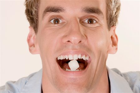Portrait d'un jeune homme avec des bonbons dans la bouche Photographie de stock - Premium Libres de Droits, Code: 625-00850220