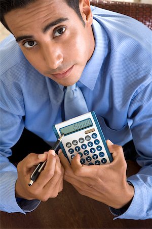 Portrait of a businessman holding a calculator and a pen Stock Photo - Premium Royalty-Free, Code: 625-00850276