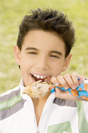 Portrait of a boy eating a chicken drumstick Stock Photo - Premium Royalty-Free, Code: 625-00850272