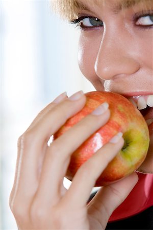 Portrait of a young woman biting an apple Stock Photo - Premium Royalty-Free, Code: 625-00850549