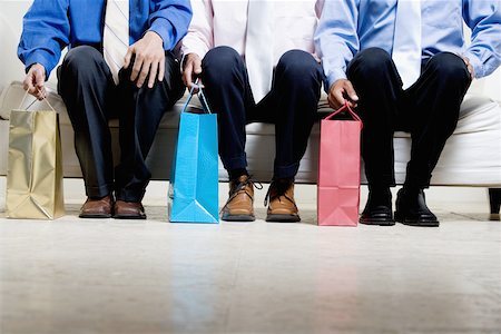 Low section view of three businessmen sitting with shopping bags Stock Photo - Premium Royalty-Free, Code: 625-00850542