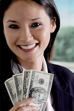 Portrait of a businesswoman holding American paper currency Fotografie stock - Premium Royalty-Free, Codice: 625-00850587
