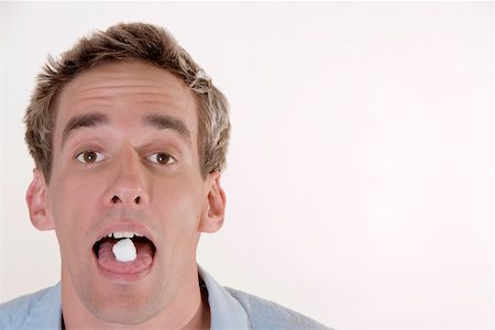 Portrait d'un jeune homme avec des bonbons dans la bouche Photographie de stock - Premium Libres de Droits, Code: 625-00850625