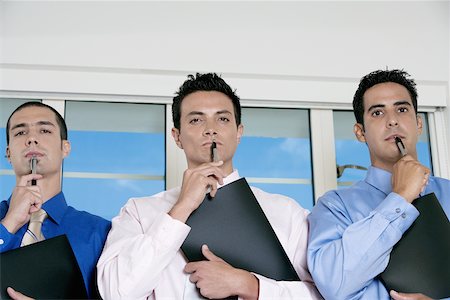 simsearch:625-02931593,k - Portrait de trois hommes d'affaires maintenant stylos contre leurs visages Photographie de stock - Premium Libres de Droits, Code: 625-00850948