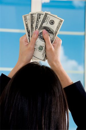 Rear view of a businesswoman holding American paper currency Stock Photo - Premium Royalty-Free, Code: 625-00851016