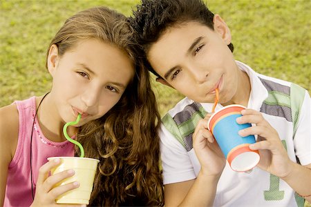 Portrait of a brother and sister drinking with straws Stock Photo - Premium Royalty-Free, Code: 625-00851273