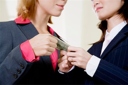 Mid section view of two businesswomen holding a dollar bill Stock Photo - Premium Royalty-Free, Code: 625-00851305