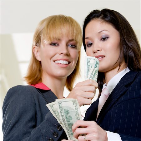 simsearch:625-00850993,k - Low angle view of a businesswoman showing a dollar bill to another businesswoman Stock Photo - Premium Royalty-Free, Code: 625-00851328