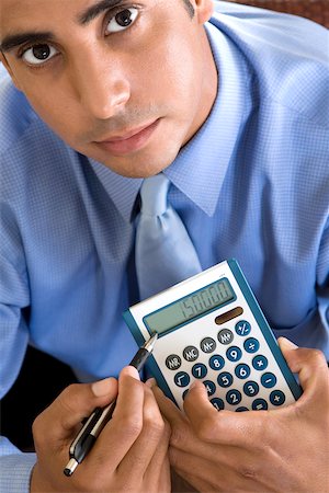 Portrait of a businessman holding a calculator and a pen Stock Photo - Premium Royalty-Free, Code: 625-00851414