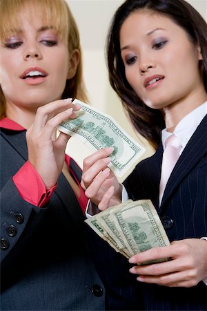 simsearch:625-01095402,k - Low angle view of two businesswomen holding American paper currency Foto de stock - Sin royalties Premium, Código: 625-00851479
