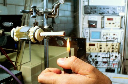 Close-up of a person's hand lighting a cigarette on a testing machine in a manufacturing plant, Richmond, Virginia, USA Stock Photo - Premium Royalty-Free, Code: 625-00899016