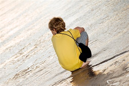 Rear view of a boy squatting on the beach Stock Photo - Premium Royalty-Free, Code: 625-00899646
