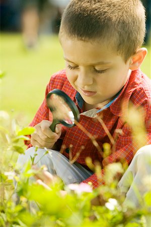 Close-up of a boy looking at a plant through a magnifying glass Stock Photo - Premium Royalty-Free, Code: 625-00899667