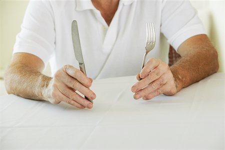 Mid section view of a senior man holding a table knife and a fork Stock Photo - Premium Royalty-Free, Code: 625-00900157