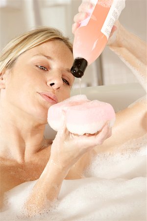 Close-up of a young woman pouring soap on a bath sponge Stock Photo - Premium Royalty-Free, Code: 625-00900642