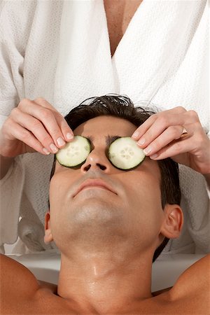 Mid section view of a massage therapist putting slices of cucumber on a young man's eyes Stock Photo - Premium Royalty-Free, Code: 625-00900653