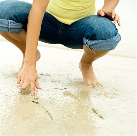 Vue en coupe basse d'une jeune fille écrivant dans le sable avec son doigt Photographie de stock - Premium Libres de Droits, Code: 625-00900699