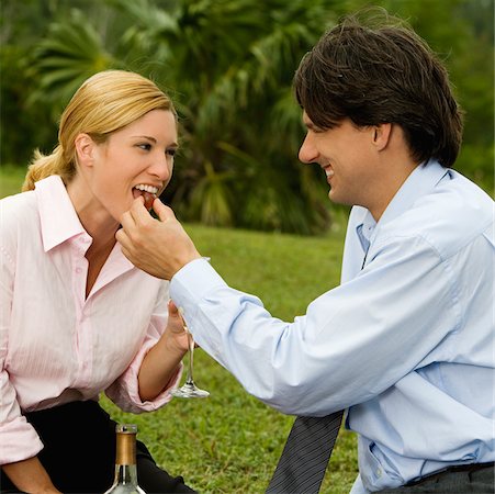 Side profile of a businessman feeding a cherry to a businesswoman Stock Photo - Premium Royalty-Free, Code: 625-00900724