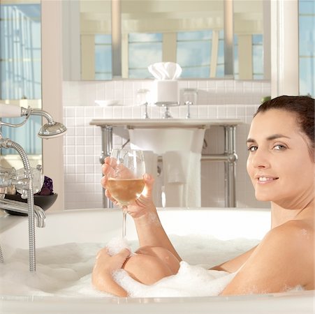 Portrait of a young woman holding a glass of a wine in a bathtub Stock Photo - Premium Royalty-Free, Code: 625-00900762