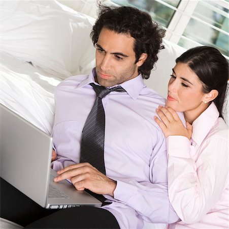 Close-up of a businessman and a businesswoman sitting on the bed using a laptop Stock Photo - Premium Royalty-Free, Code: 625-00900919