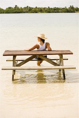 Rear view of a teenage girl sitting on a wooden bench on the beach Stock Photo - Premium Royalty-Free, Code: 625-00901005
