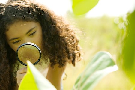 Close-up of a girl looking through a magnifying glass Stock Photo - Premium Royalty-Free, Code: 625-00901083