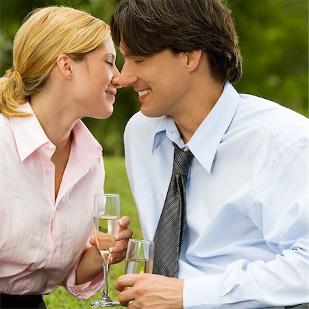 Close-up of a businessman and a businesswoman sitting in the park holding champagne flutes Stock Photo - Premium Royalty-Free, Code: 625-00901438