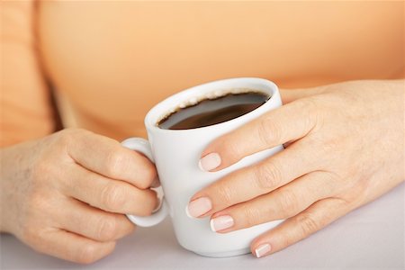 full cup - Mid section view of a woman's hand holding a cup of coffee Stock Photo - Premium Royalty-Free, Code: 625-00901430